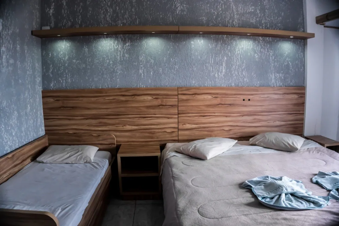 Habitación del Hotel Bauer con cama doble, cama individual y cabecero de madera