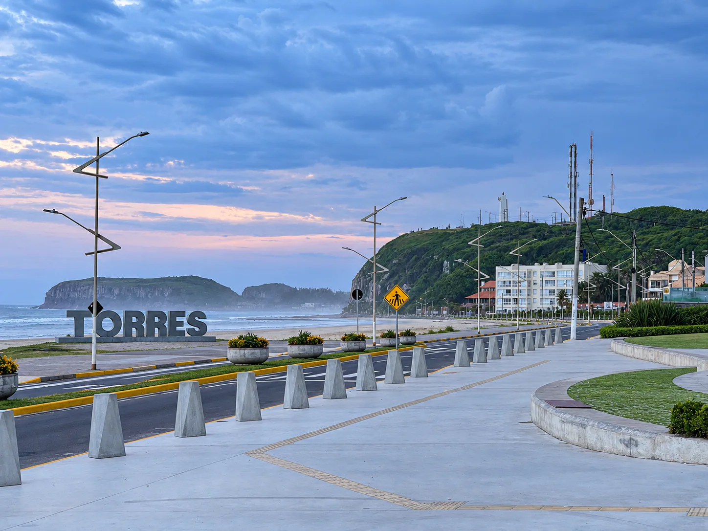 Passeio e bancos de concreto da Praça Borges de Medeiros, com a Prainha e o Morro do Farol ao fundo.