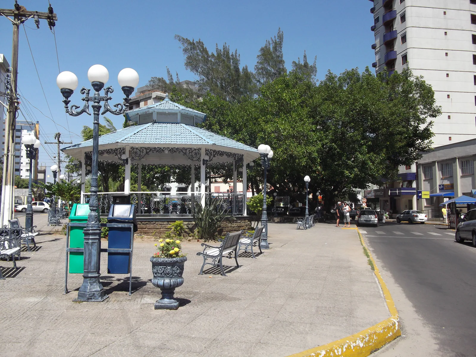 Coreto de telhado azul, bancos e árvores da Praça XV de Novembro.