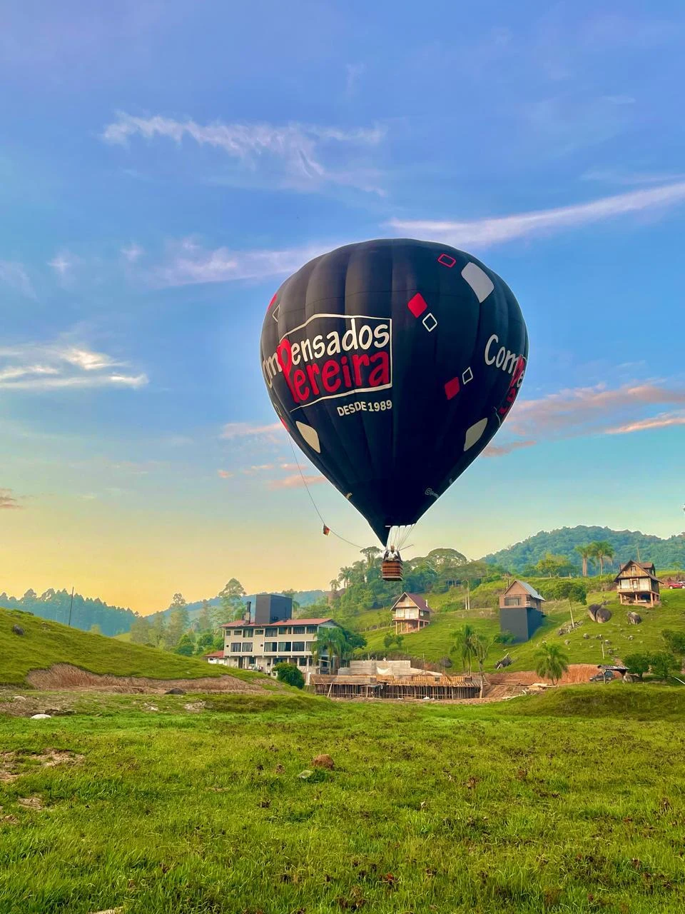 Globo en vuelo sobre una zona con césped y edificios