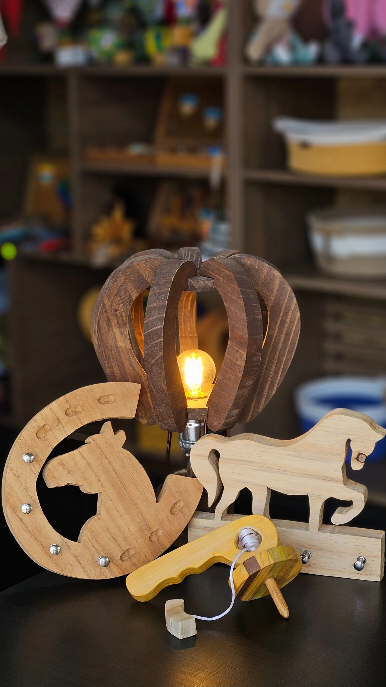 Illuminated balloon-shaped lamp, wooden horse-themed pieces and a spinning top on the counter.